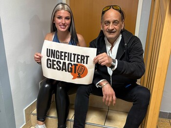 Natalie und Sigi sitzen auf Treppen mit einem Schild "ungefiltert gesagt"